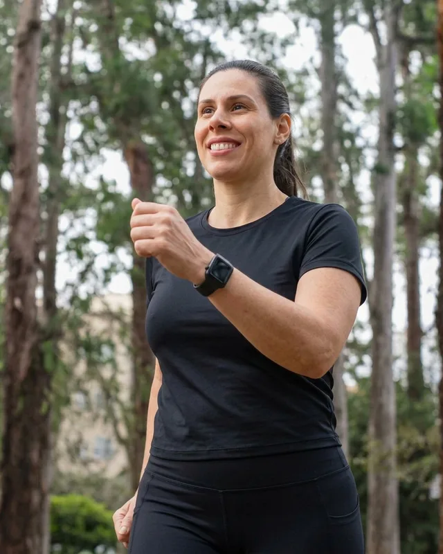 Mulher caminhando no parque de manhã, sorrindo